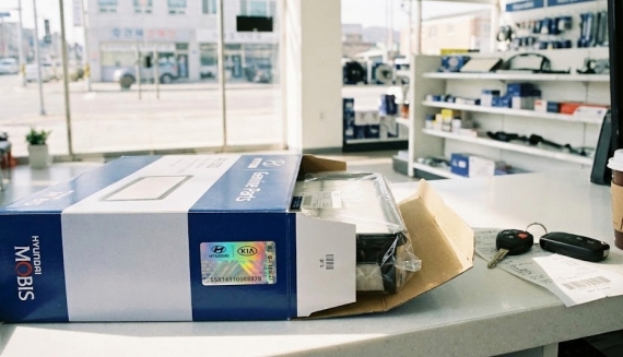 자동차 부품 대리점에서 구매한 순정 부품 박스와 홀로그램 스티커